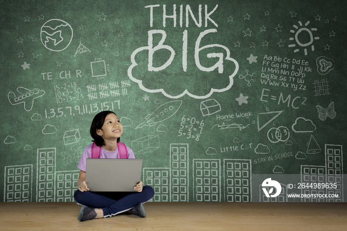 Cute schoolgirl looking at word of think big