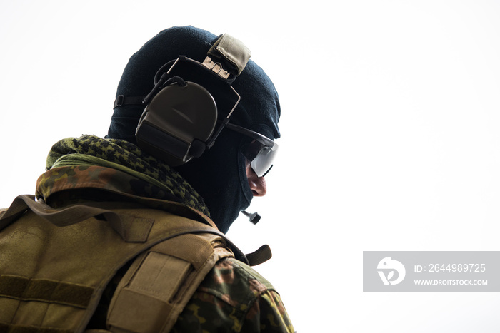 Side view serious defender telling by special microphone while wearing balaclava. Communication and military concept. Isolated and copy space