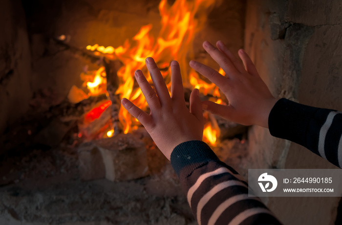 a child is warming their hands by the fire in the fireplace