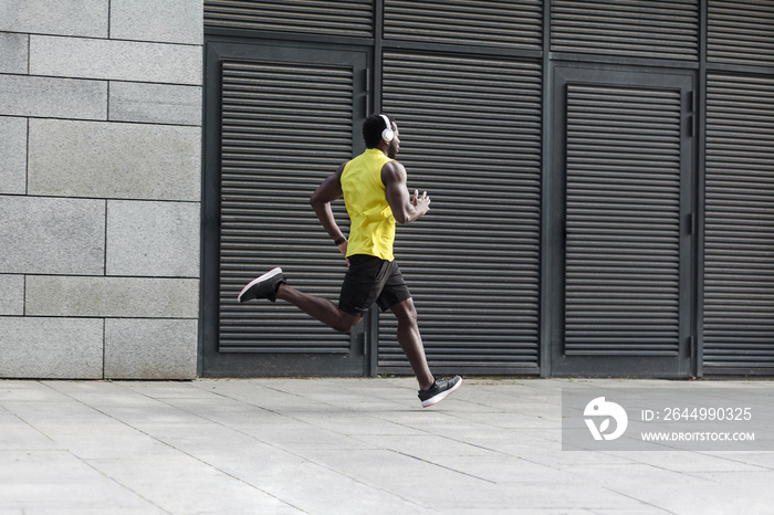 Sporty man in yellow t-shirt running sunset outdoors spring