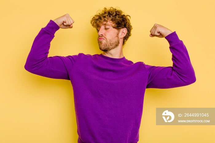 Young caucasian man isolated on yellow background showing strength gesture with arms, symbol of feminine power