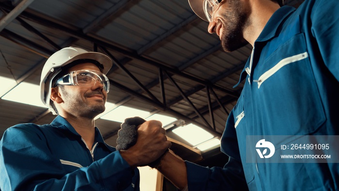 Two skillful factory engineer or worker showing teamwork and partnership . Industrial people and manufacturing labor concept .