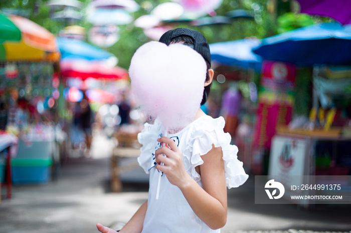 Portrait Asian girl eating the pink cotton candy at the outdoor market