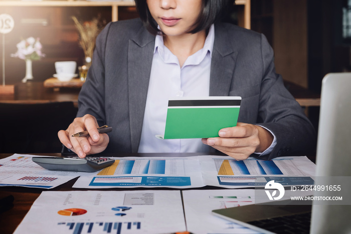 Saving and growth money concept bookkeeper using calculator, laptop computer and holding passbook to audit money account of her.