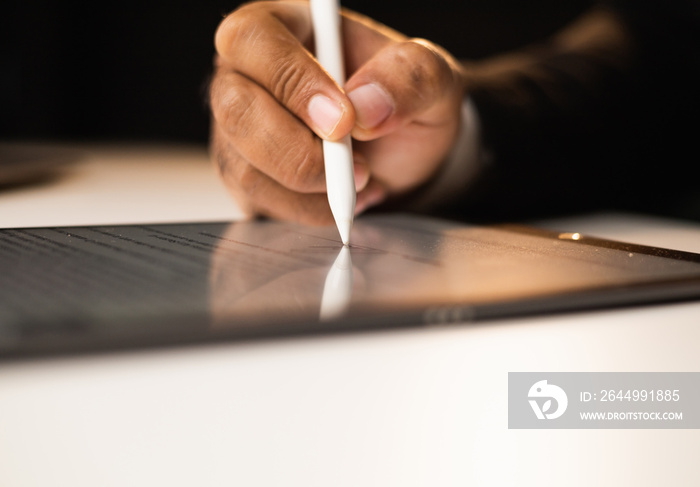 Close up businessman hand electronic Signature on Tablet by Stylus. Write business agreement of contract. Man signing contract on tablet. Business and technology concept.