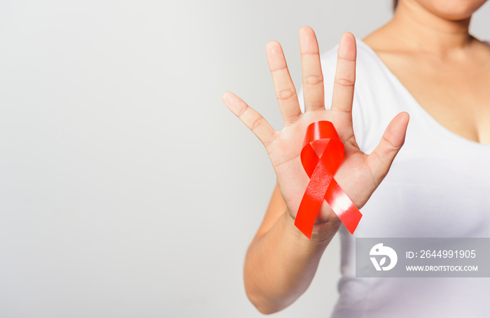 Closeup of female with red ribbon Support HIV AIDS on hand