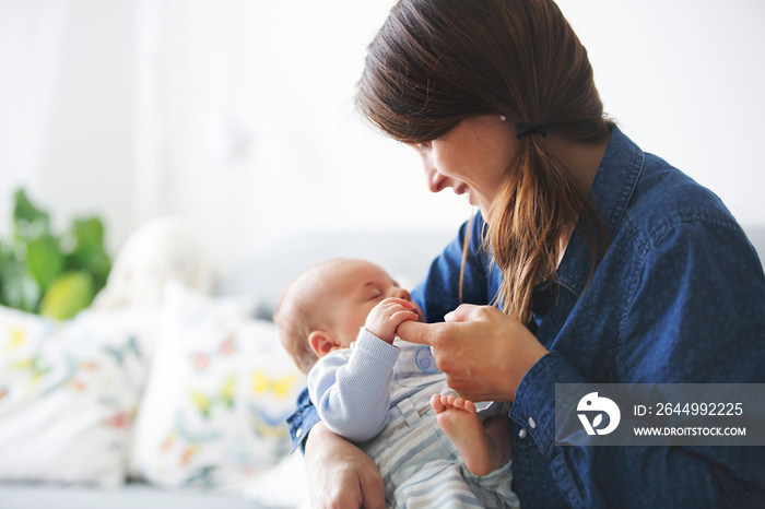 Young mother, kissing her newborn baby boy at home