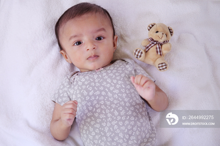 Newborn baby boy with teddy bear on bed