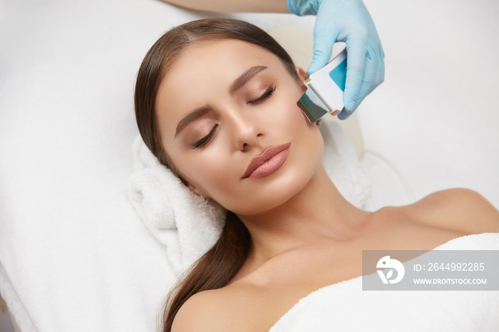 Cosmetology. Closeup Of Female Face having facial treatment in beauty salon. Cosmetic procedures in spa clinic.