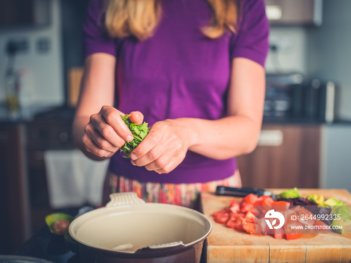 Young woman preparing salad with tomatoes and avocado