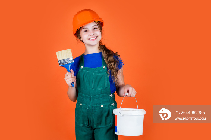 Working in repair shop. kid wear helmet on construction site. teen girl painter with painting bucket and brush. child on repairing work. concept of renovation in workshop. busy professional carpenter