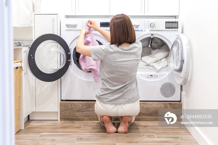 Woman Loading Dirty Clothes In Washing Machine For Washing In modern Utility Room