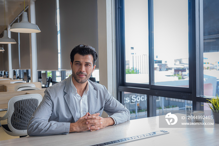 Businesss man sit in modern office look at camera