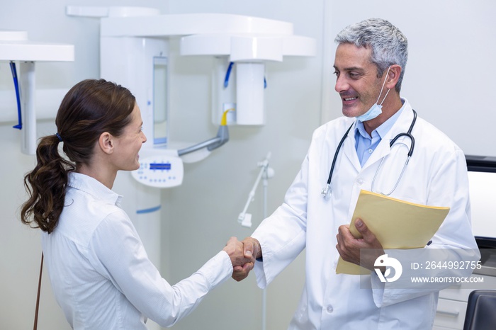 Dentist shaking hand with female patient