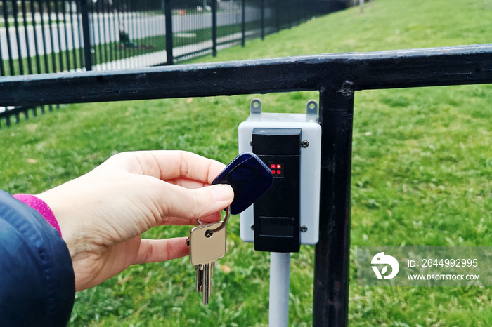 A person holding attaching key fob to open door. Closeup of a human hand with magnetic key fob for allowing access. Secutity system mechanism technology.