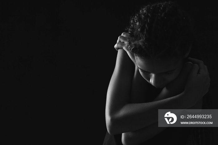 Sad African-American girl on dark background. Stop racism