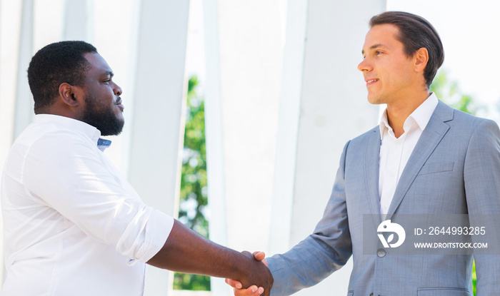 Finance, business and cooperation concept. Two successful businessmen are talking on the street. Office workers are discussing business issues outdoor.