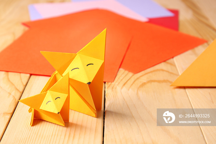 Cute origami foxes on wooden table