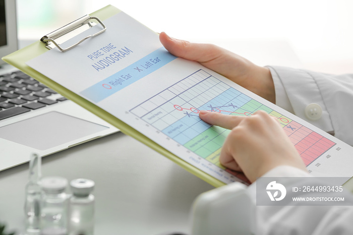 Female doctor with audiogram in clinic, closeup