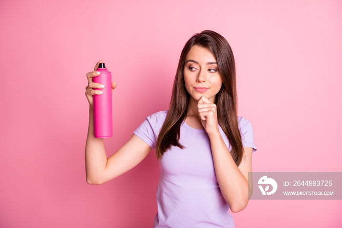 Portrait of adorable young lady hold hairspray touch chin look empty space dressed casual wear isolated on pink color background