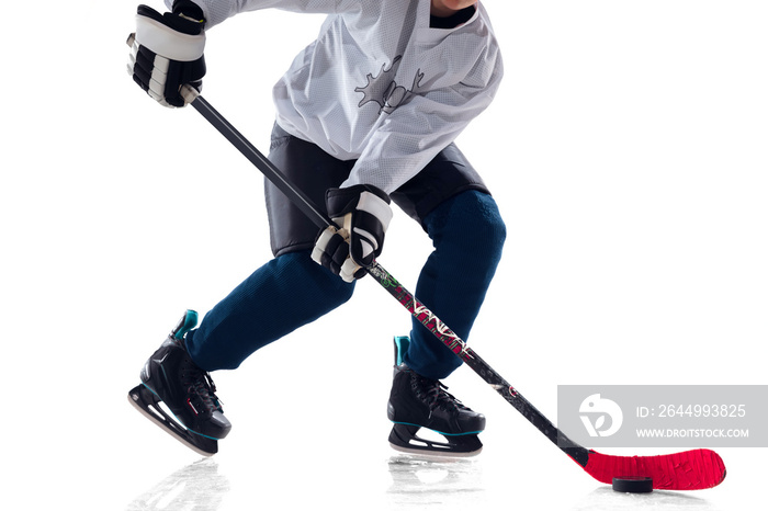 Unrecognizable male hockey player with the stick on ice court and white background. Sportsman wearing equipment and helmet practicing. Concept of sport, healthy lifestyle, motion, action. Close up.