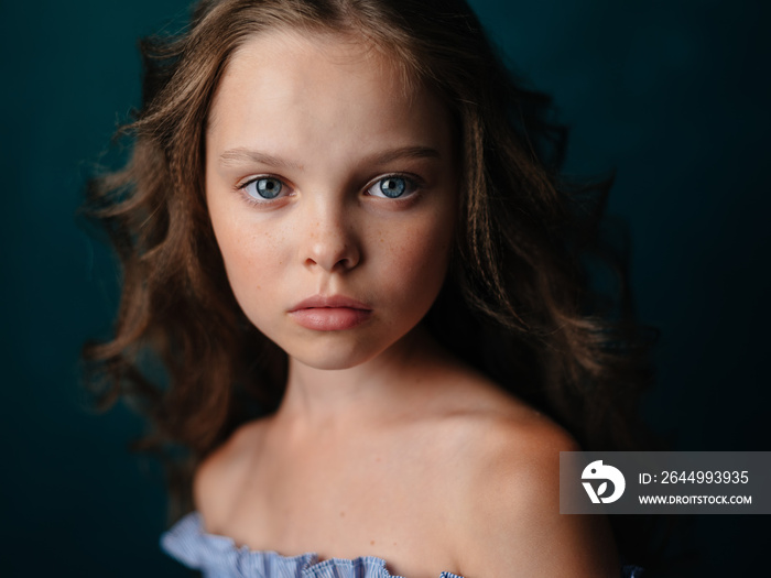 Portrait of a beautiful little girl in a sundress on a dark background close-up