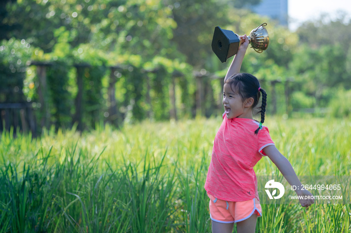 Asian girl was overjoyed and lifted the golden trophy over her head, celebrate successes and victories at an outdoor park