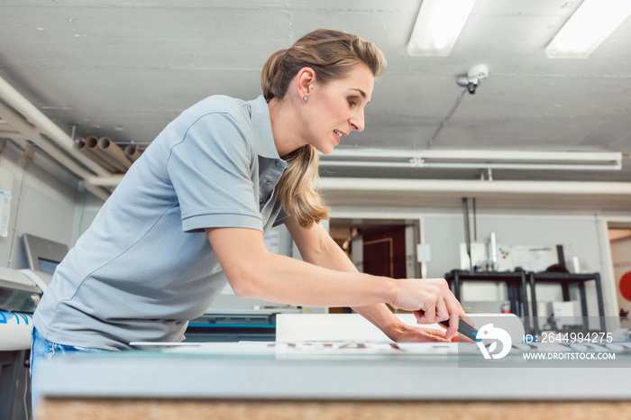 Woman cutting signs or vinyl wraps producing advertising materials