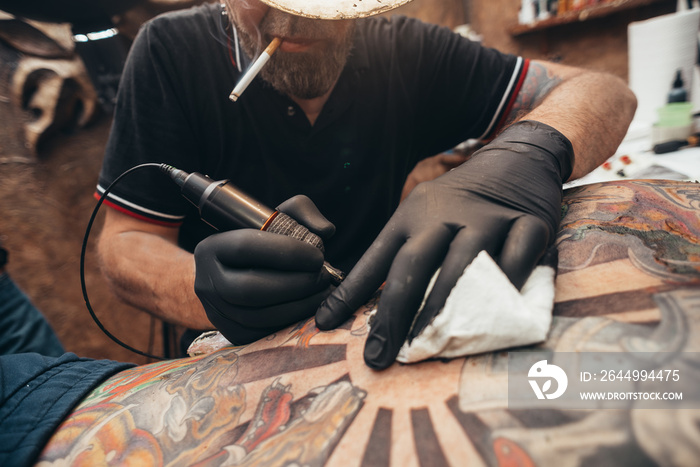 Close up tattoo machine. Tattooing. Man creating picture on his back by a professional tattoo artist.