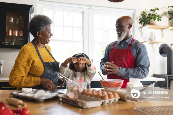 Image of happy african american grandparents and granddaughter baking in kitchen