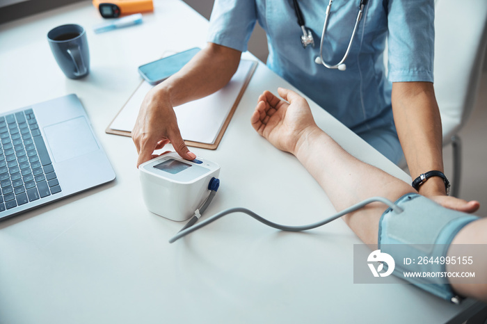 Female doctor checking patient blood pressure in clinic