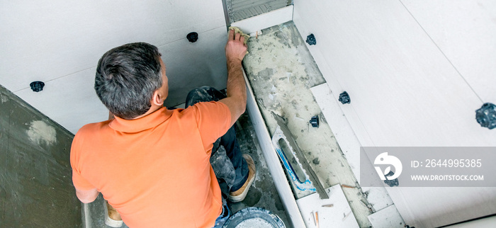 Handwerker verlegt Fliesen in einem modernen Haus