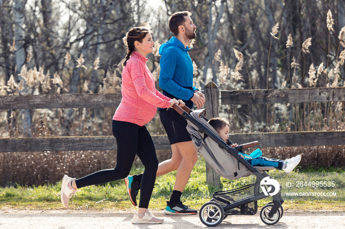 Sporty young couple with her little son running while enjoying the time together outdoor.