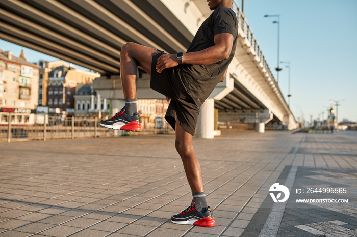 Cropped side view of black sportsman stretch leg