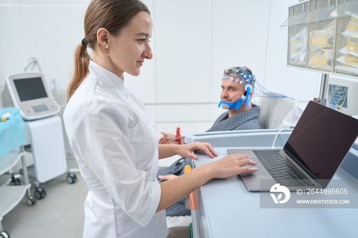 Woman diagnostician at the workplace conducts EEG - electroencephalography