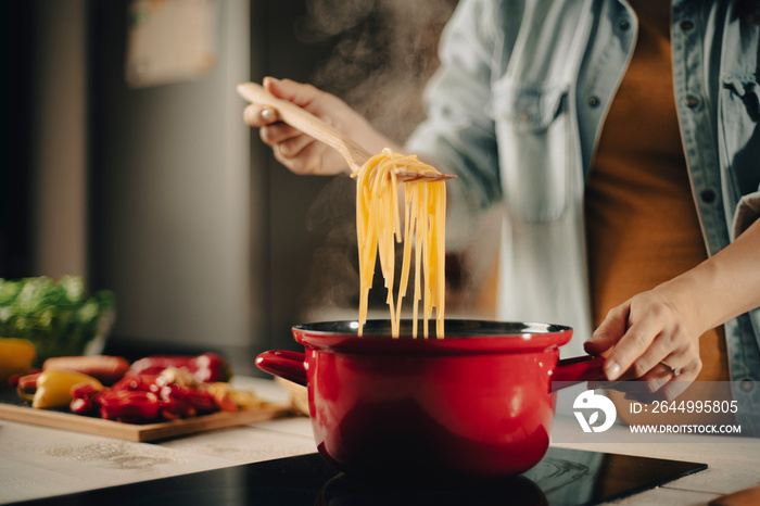 Beautiful pregnant woman preparing delicious food. Smiling woman cooking at home.