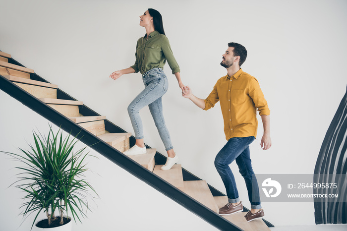 Full body profile photo of handsome guy and his pretty lady leading macho to bedroom going up stairs in modern interior hotel room indoors wear casual clothes