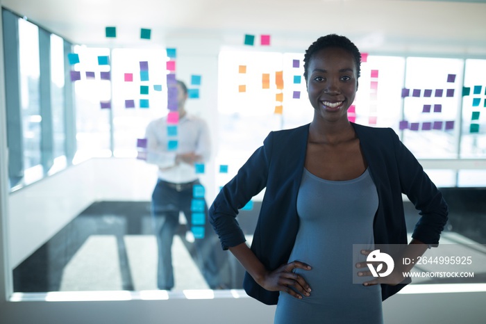 Female executive standing with hands on hip in office