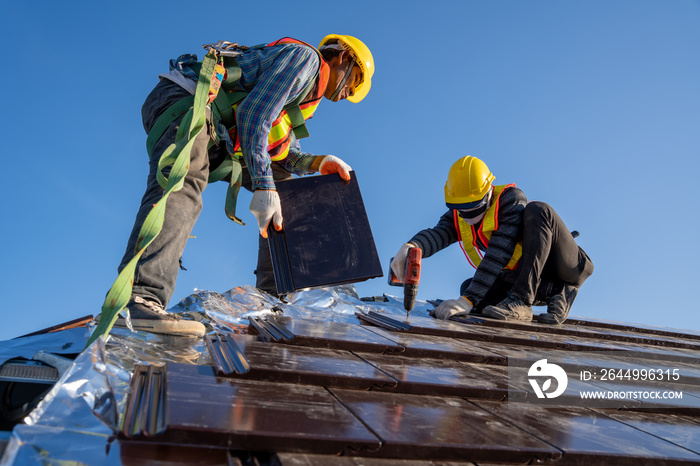 Two work construction worker install new ceramic tile roof with Roofing tools electric drill used in the construction site.