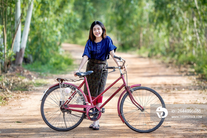 Asian farmer girl dressed in traditional local and her bicycle.