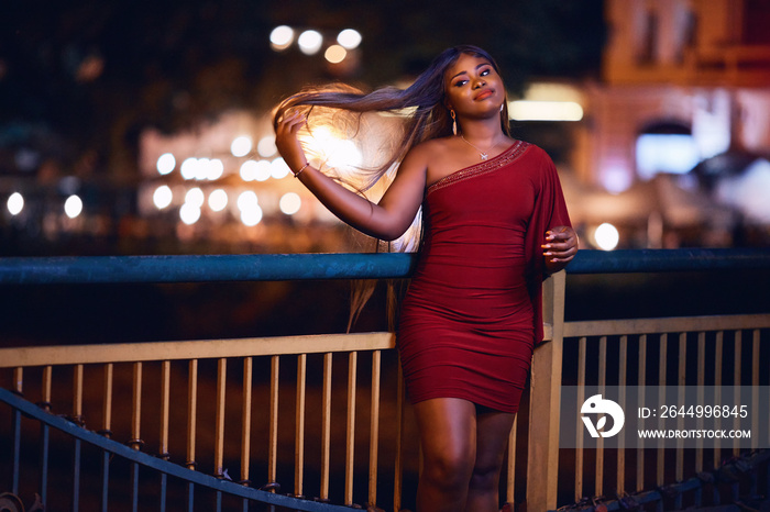 elegant african american woman in evening dress on a night city street