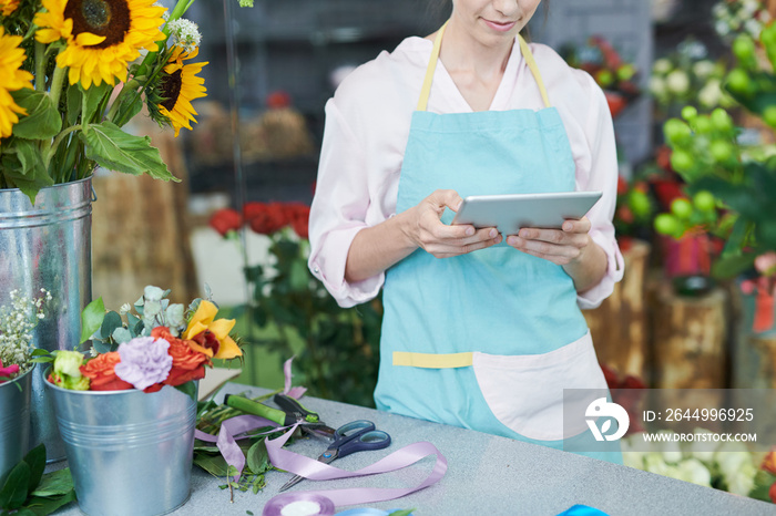 Mid section portrait of unrecognizable florist using digital tablet in shop