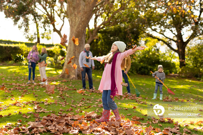 Image of happy multi generation caucasian family having fun with leaves in autumn garden