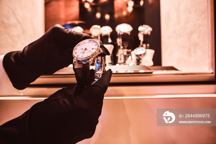 Close-up of the seller’s hands in gloves shows the exclusive men’s watch from the new collection in the luxury jewelry store