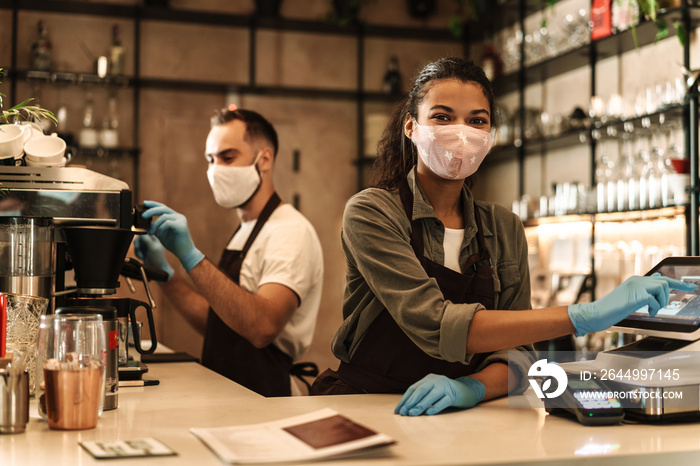 Two baristas wearing medical mask serving coffee