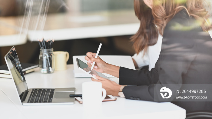 Side shot of confidence woman while giving a consult to young businesswoman next to her by tablet.