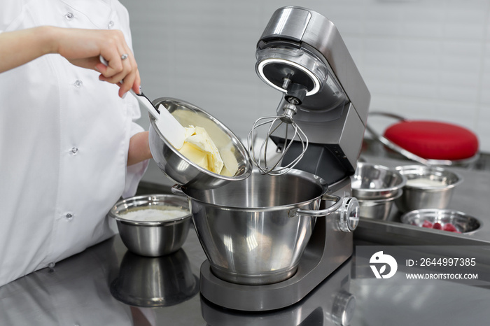 Pastry chef adds butter to the kitchen machine, mixer