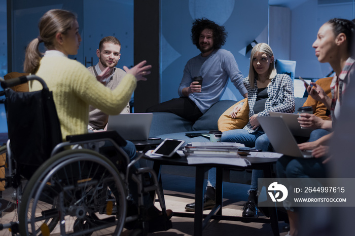 Handicapped young woman with colleagues working in office. She is smiling and passionate about the workflow. Performing in co-working space. Office people working together.