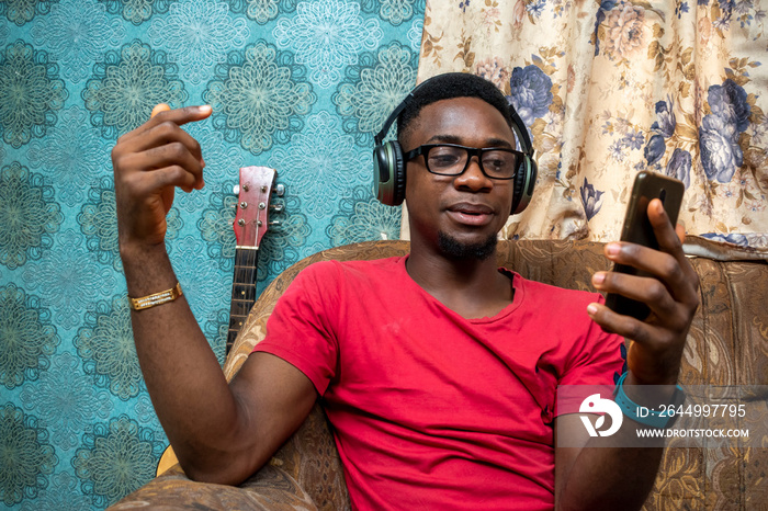 african man making a live video, wearing a headphones, indoors, making gestures as he talks