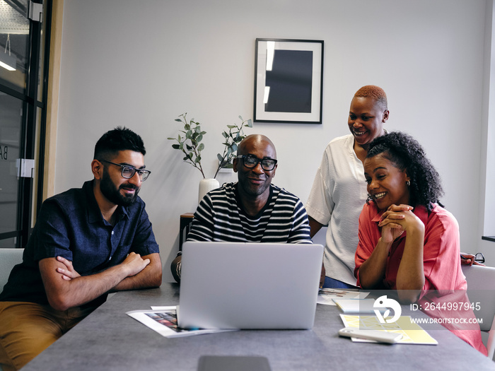 Colleagues looking at laptop during business meeting